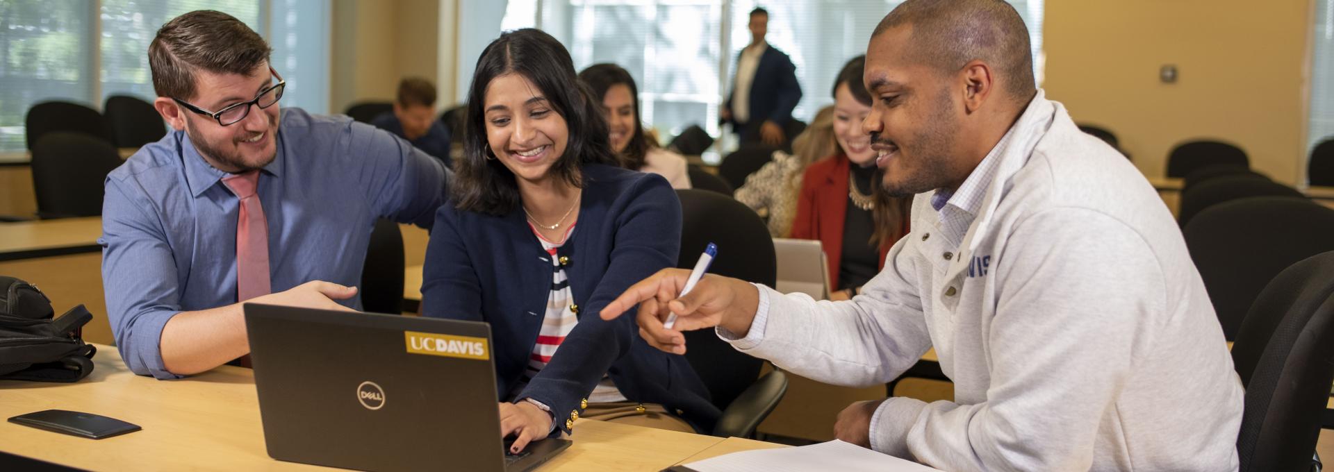 Students sitting and looking at a laptop in a classroom setting