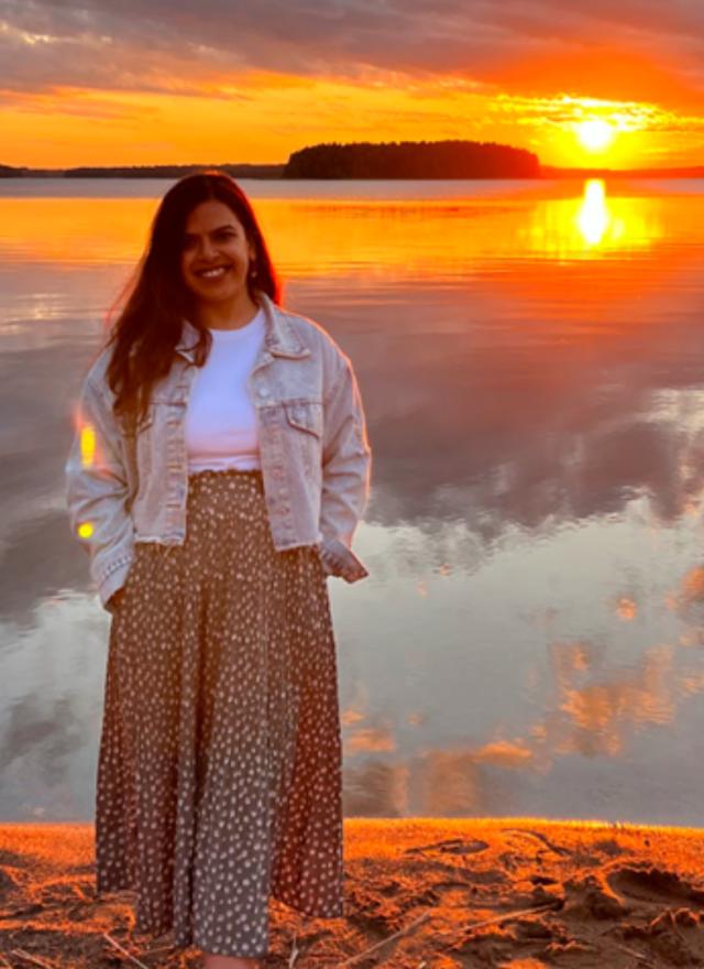 Prachi Mishra standing in front of a lake at sunset