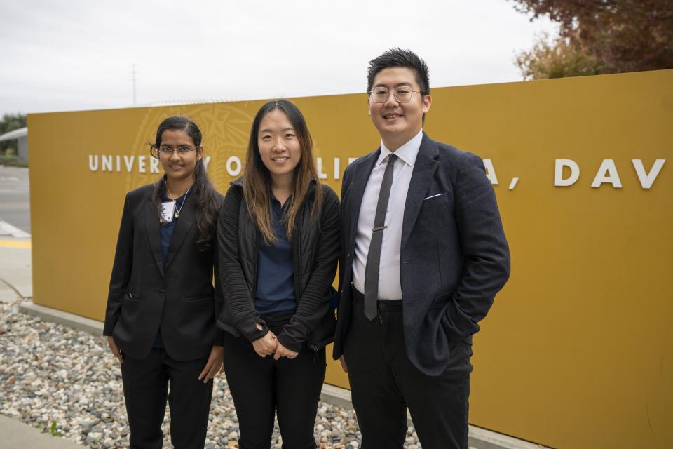 Three people standing in front of the UC Davis welcome sign