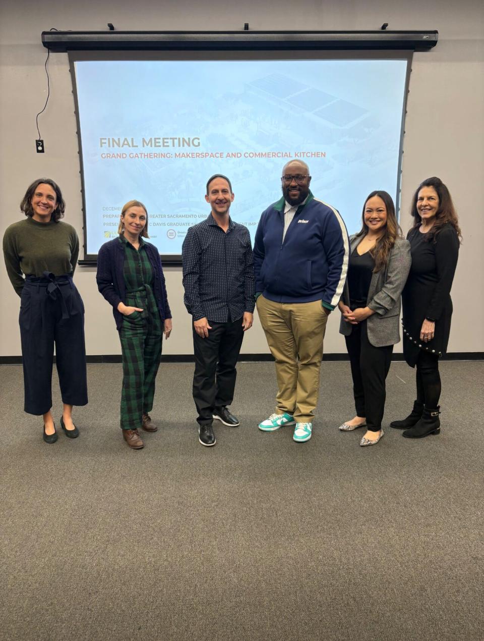 Liza Santa Ana and MBA students in front of a presentation screen