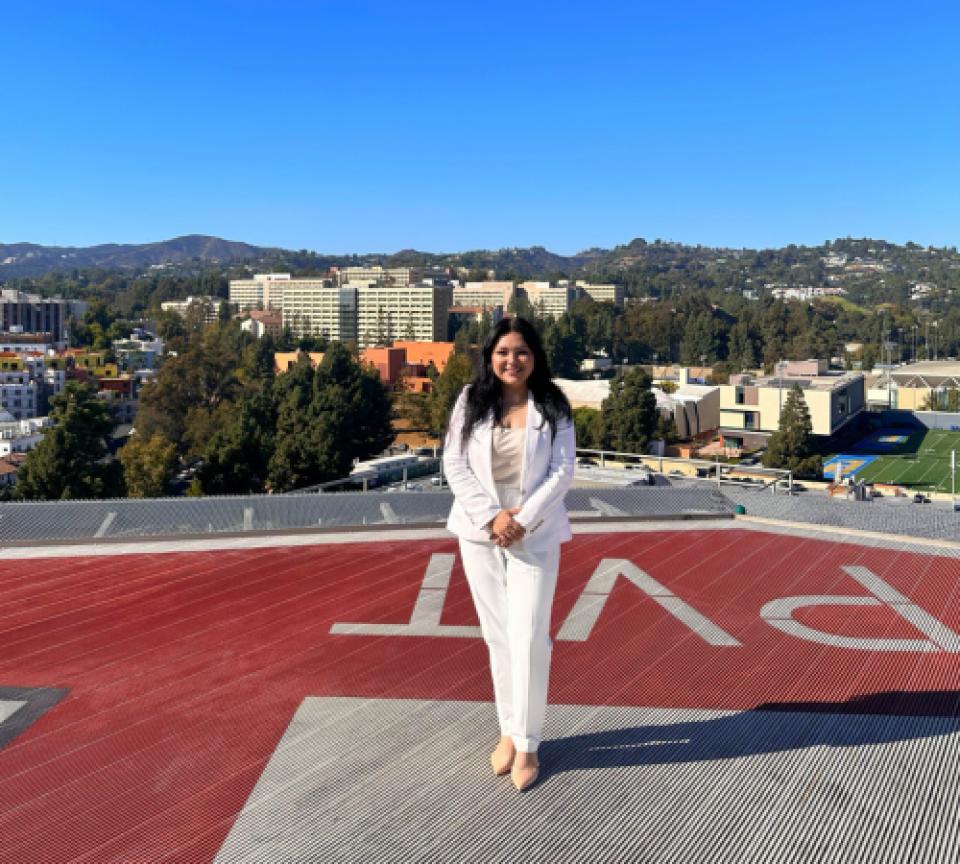 Marissa Hernandez standing on a helipad at UCLA Health with green hills and buildings in the background